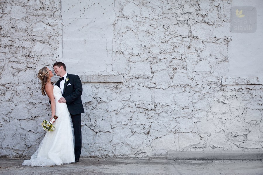 Bride and groom by a gray wall